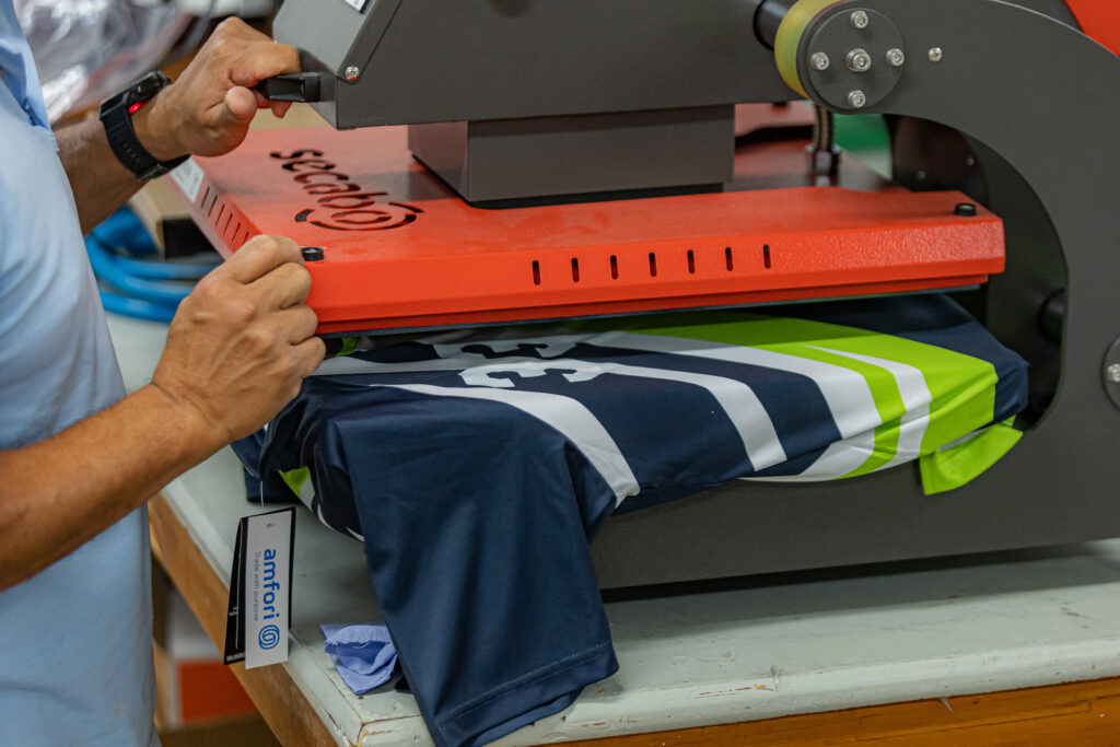 Heat pressing numbers onto a sublimated shirt made of recycled fabric.