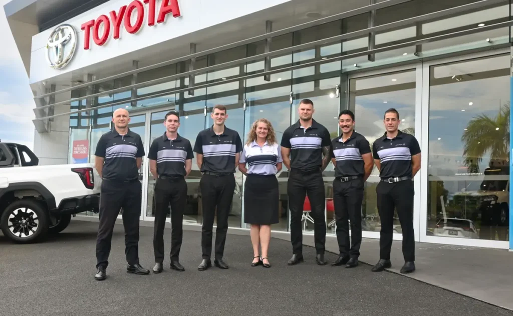 Pacific Toyota team standing out the front of the dealership wearing grey and black custom corporate uniforms by Uniform Link